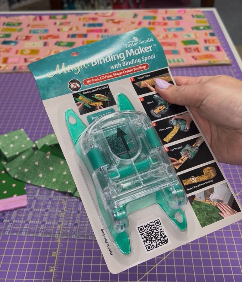 Magic Binding Maker with Binding Spool packaging held by a hand on a colorful background