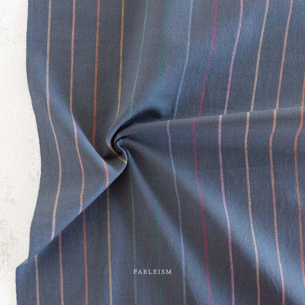 Lucky Loom Skinny Stripe in Dark Rainbow – navy base fabric with fine vertical rainbow pinstripes, shown flat to display color and weave
