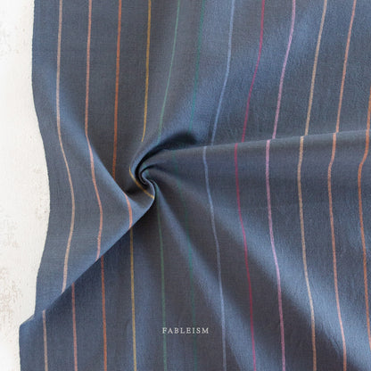 Lucky Loom Skinny Stripe in Dark Rainbow – navy base fabric with fine vertical rainbow pinstripes, shown flat to display color and weave