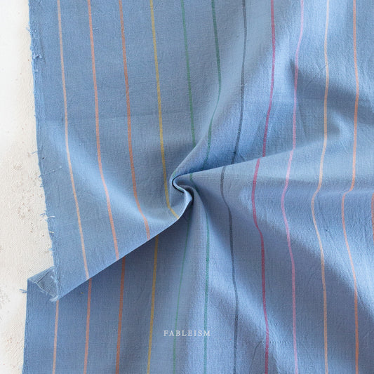 Lucky Loom Skinny Stripe in Luna – soft blue cotton fabric with delicate vertical rainbow stripes